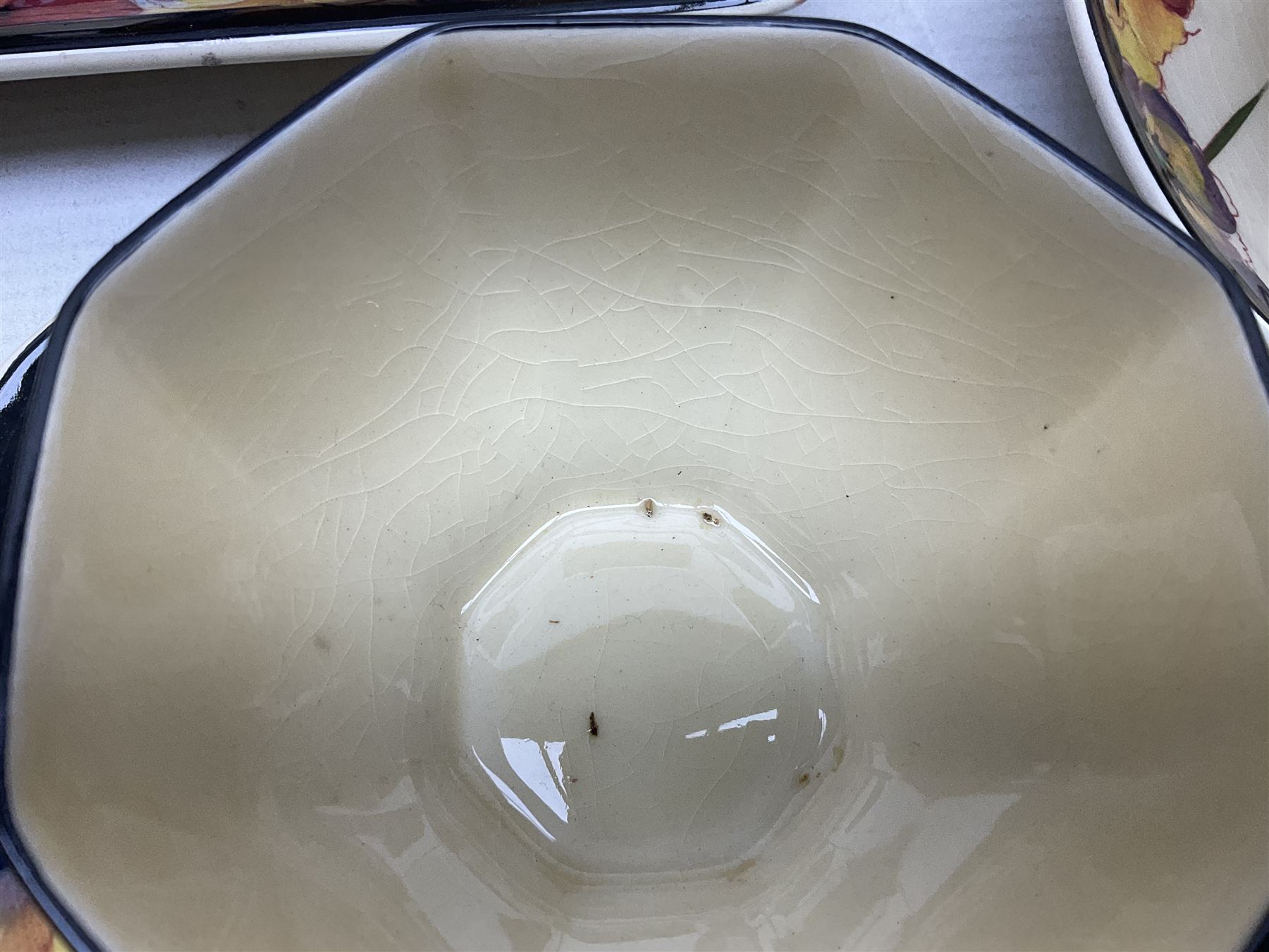 Early 20th century Art Deco Royal Doulton Pansies pattern octagonal teawares, comprising three larger teacups and saucers, three smaller teacups and saucers, open sucrier, two jugs, slop bowl, six side plates, two larger plates, two small circular dishes and one long twin handled rectangular dish, all with printed marks beneath, Rd No 597783, pattern no D4049