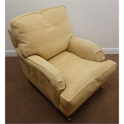  Lounge armchair, upholstered in a yellow fabric, walnut turned supports on castors, W85cm  