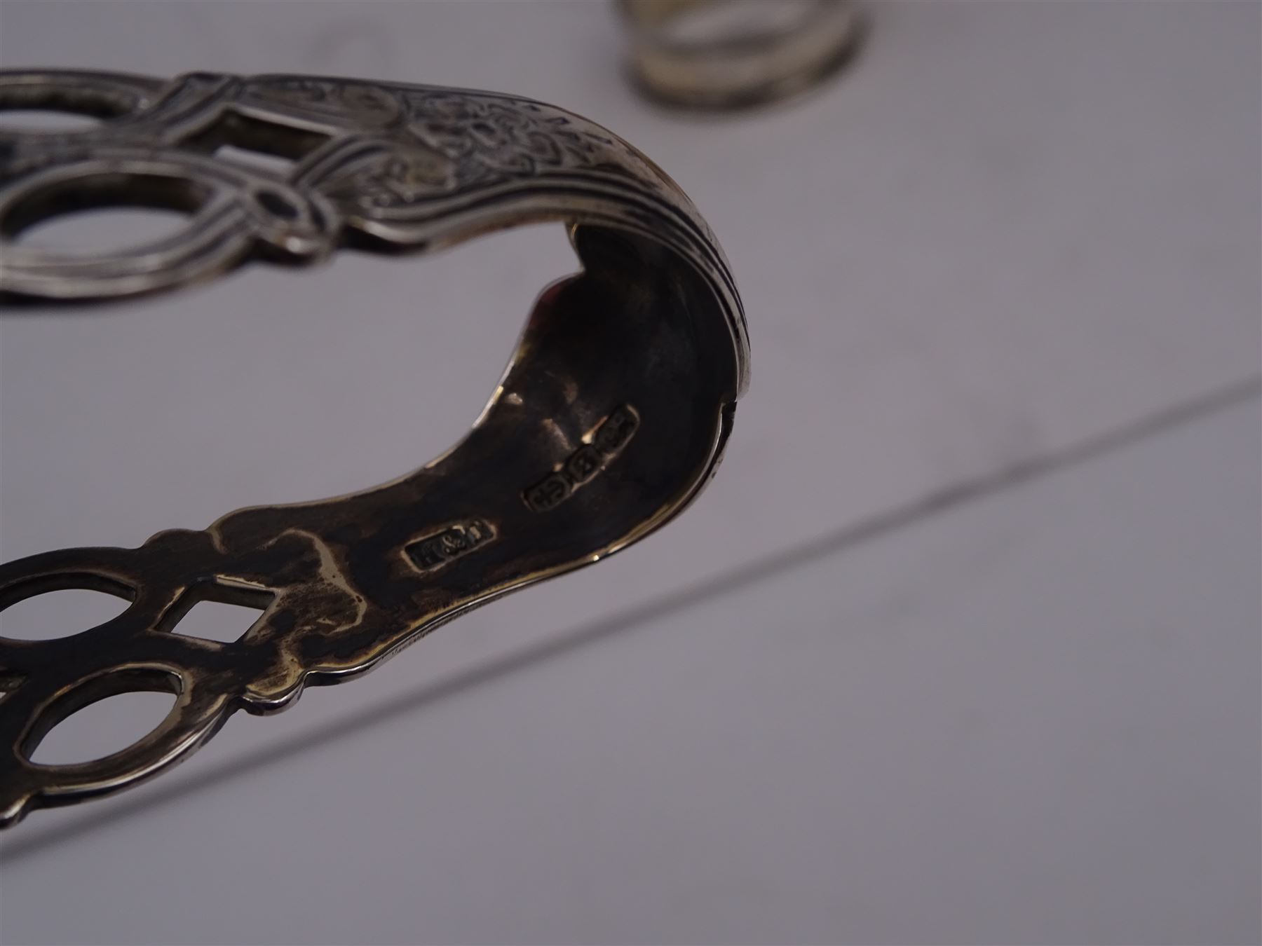 Pair of Victorian silver sugar tongs, with pierced decoration, hallmarked Hilliard & Thomason, Birmingham 1892, together with three hallmarked silver napkin rings