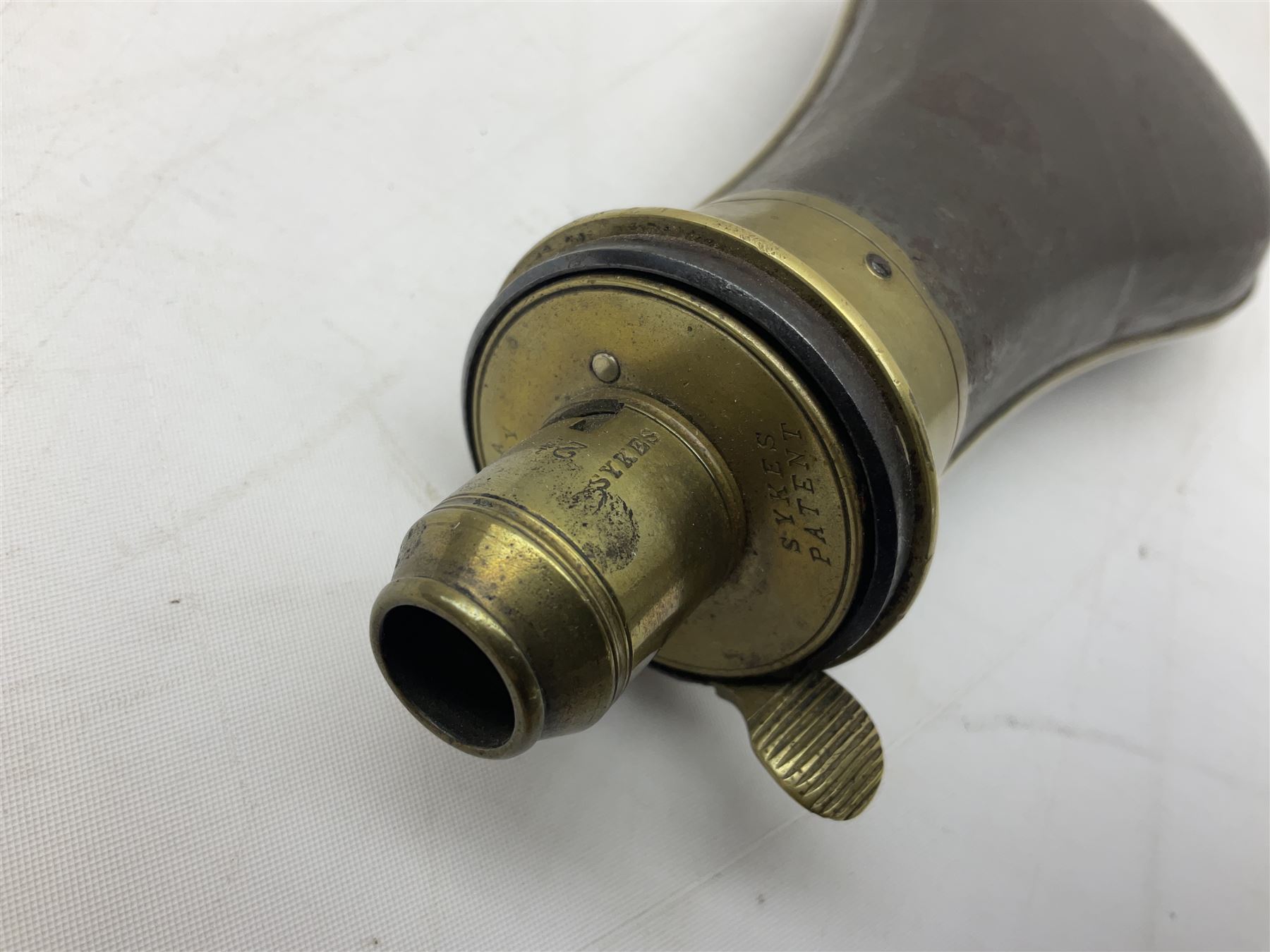 Two Sykes Patent brass mounted small load powder flasks with fire proof safety tops - one with slim plain copper body H17.5cm; the other with plain gun metal body H19cm (2)