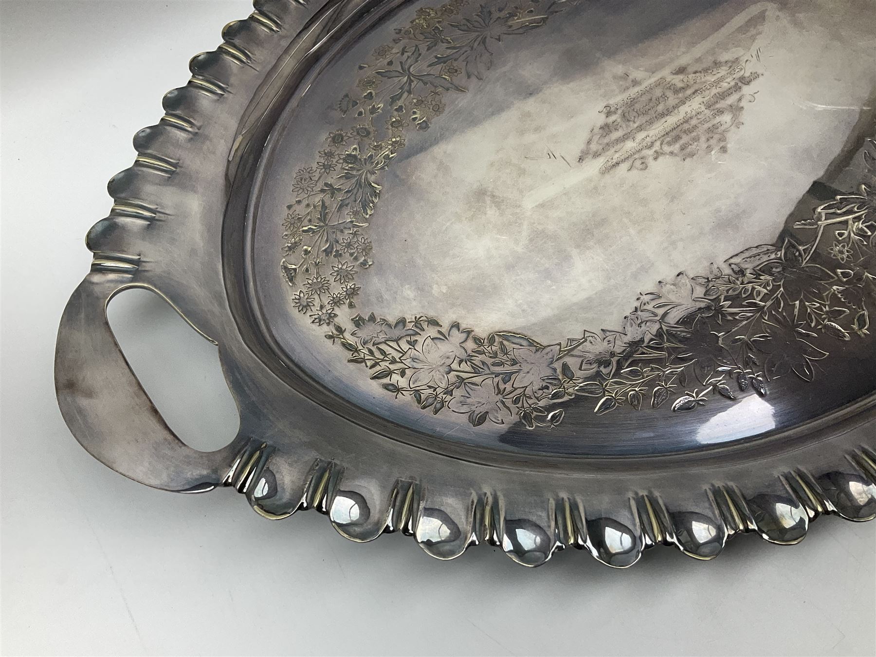 Oval silver plate twin handled tray, egg and dart edge, engraved with floral springs surrounding an central inscription, L65cm