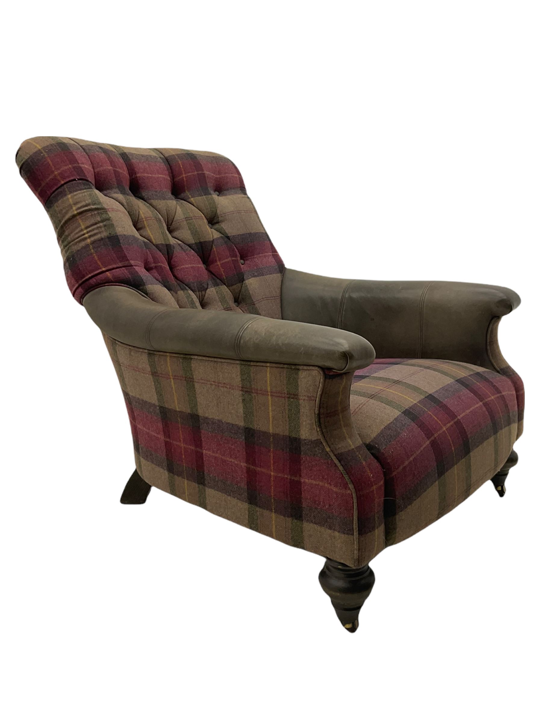 John Sankey - low armchair, buttoned back upholstered in tartan patterned fabric with contrasting grey leather, raised on turned and ebonised front feet with brass and ceramic castors, with matching foot stool