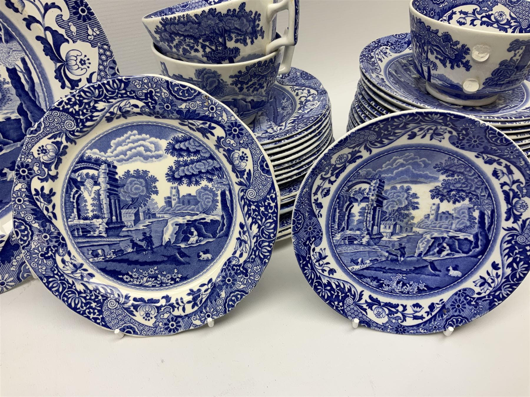 Spode blue and white Italian pattern dinner and tea wares, comprising five dinner plates, four side plates, seventeen side plates, four bowls, ten tea cups and twenty one saucers, five coffee cans and six saucers, and a flan dish, with blue and black printed marks beneath 