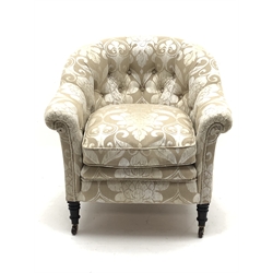  19th century tub chair with curved buttoned back, upholstered in champagne scrolled and flur de lys pattern, loose seat cushion, the ring tuned mahogany supports with brass and ceramic castors  