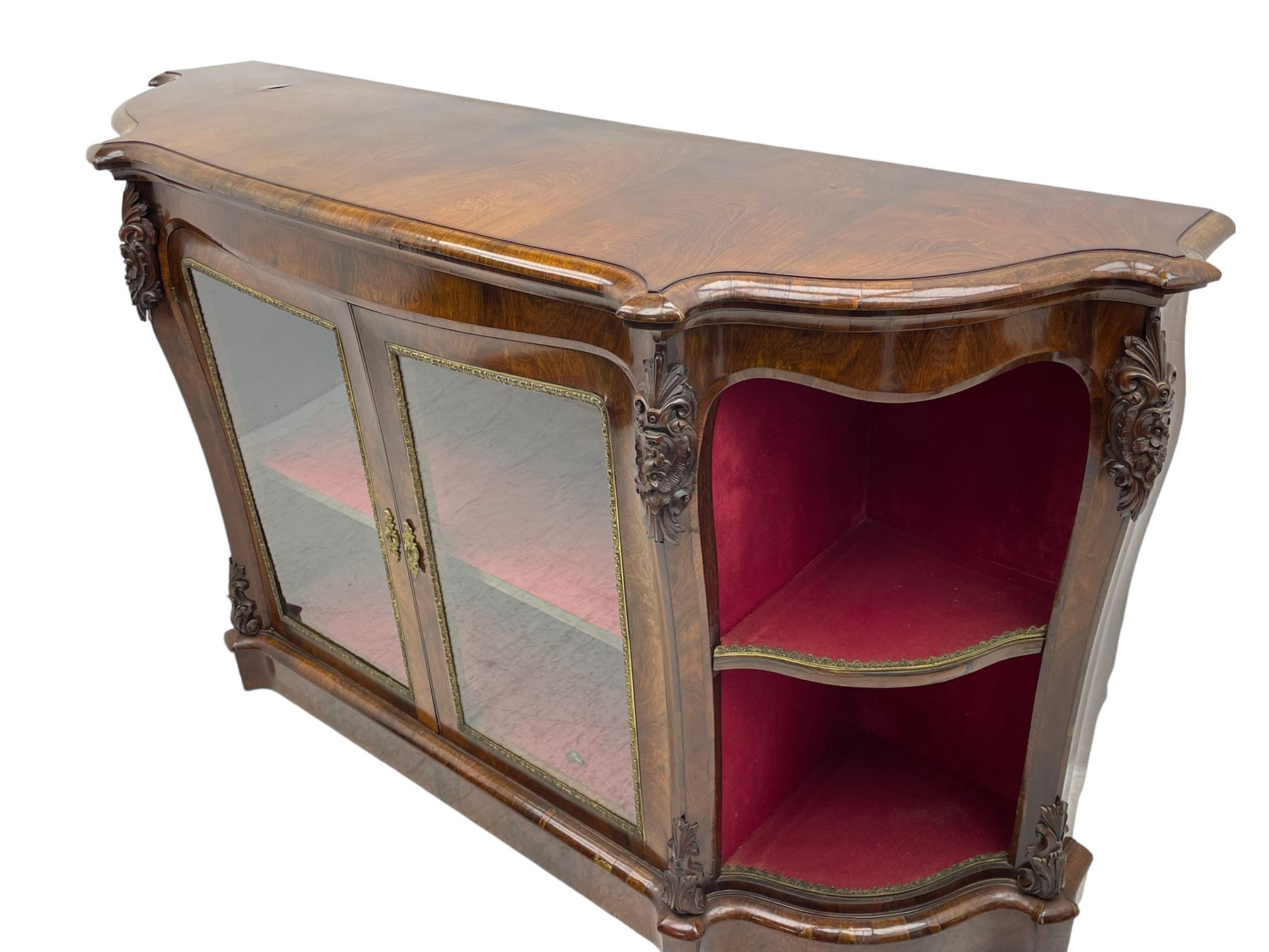 19th century rosewood buffet credenza, bombe form with shaped and moulded top, two central glazed doors with foliate moulded gilt slips, the red fabric-lined interior fitted with a single shelf, flanked by open shelves with raised gilt metal lips, the uprights decorated with shell and flower head carved cartouche mounts, acanthus leaf scroll carved lower mounts, on shaped and moulded plinth base 