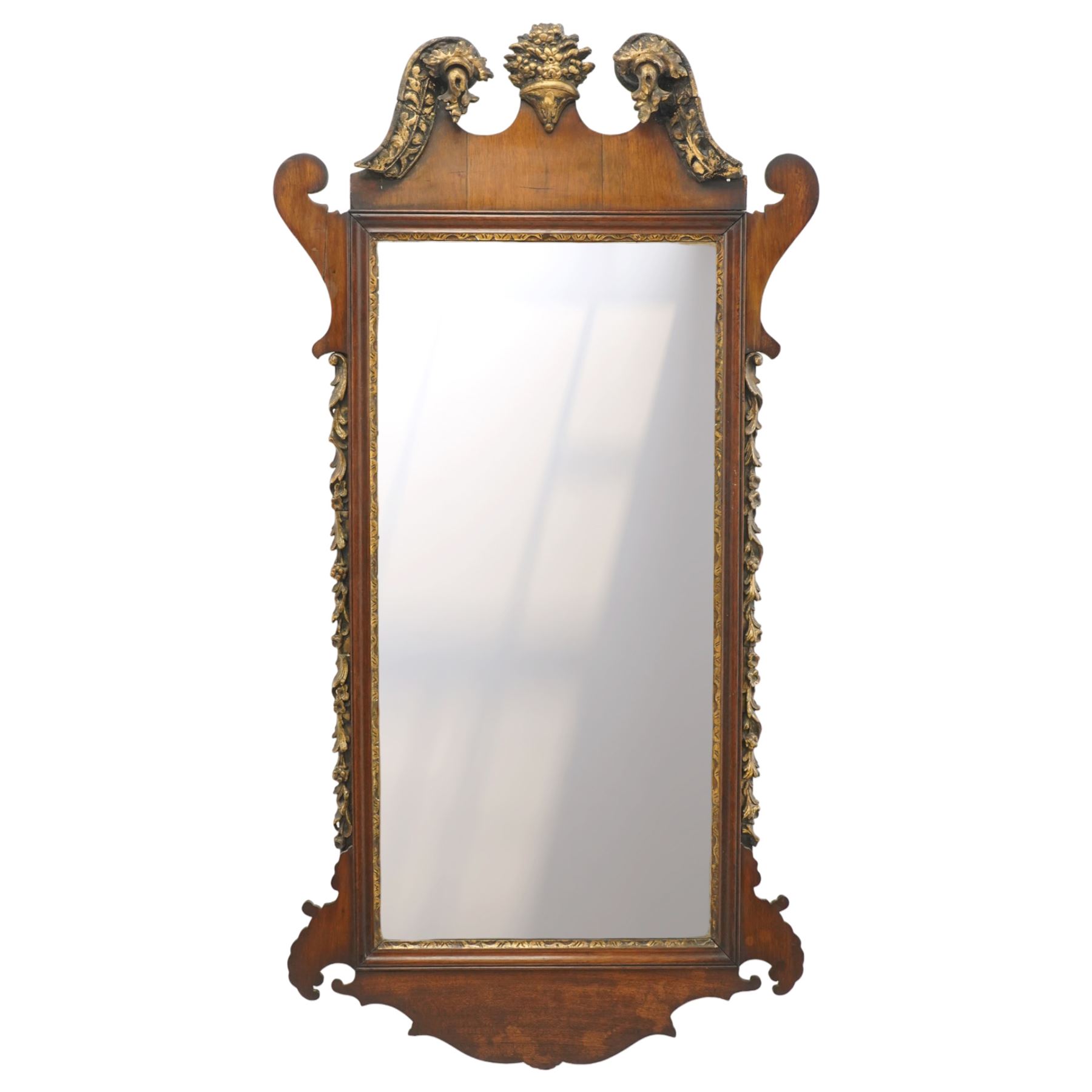 19th century Chippendale design mahogany fret mirror, broken swan neck pediment of foliate design with century bouquet in gilt finish, the rectangular bevelled plate flanked by trailing bellflower motifs, over a shaped terminal