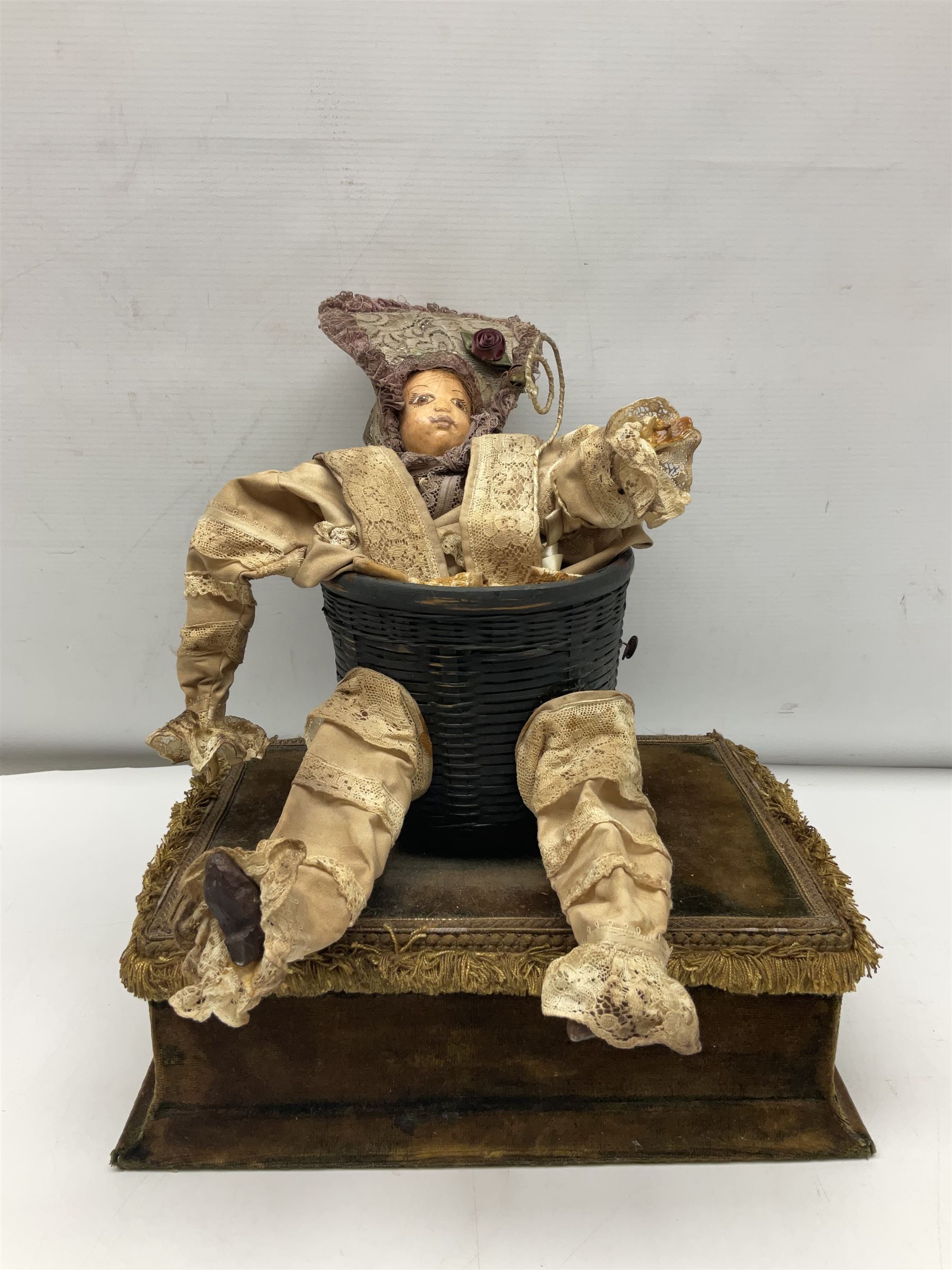 Modern reproduction automaton in the form of a baby doll in a basket clothed in Victorian style lace bloomers and frilled bonnet; clockwork action; on raised platform; with French paper label on base, 29cm wide,