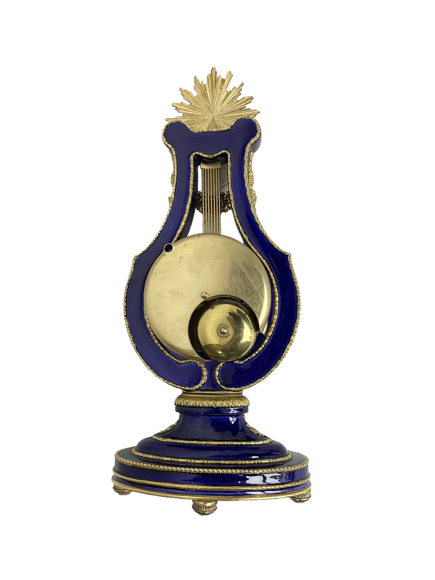 20th century V&A Marie Antionette lyre clock - Blue porcelain with gilt mounts on a  oval stepped base, dial with roman numerals and gilt hands, continental twin train spring driven movement sounding the hours and half hours on two bells. With key.