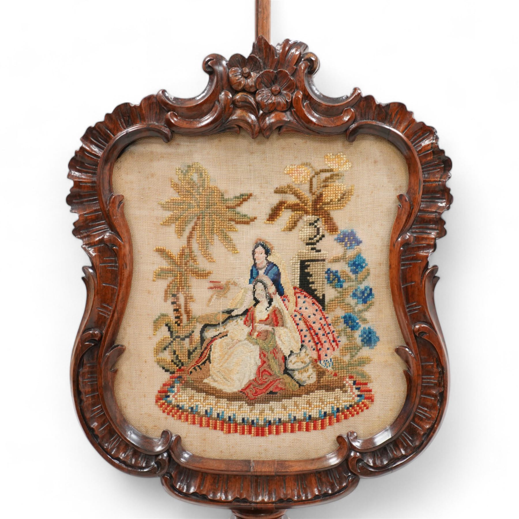 Victorian rosewood pole screen, shaped and shell carved frame enclosed needlework panel, on turned pedestal with three floral carved splayed supports with scrolled foliate terminals 
