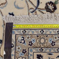 Central Persian Nain hand-knotted carpet, wool with silk highlights, ivory field with central radiating medallion surround by an intricate arrangement of scrolling vines and floral motifs, within conforming spandrels and matching border, cotton fringe ends 