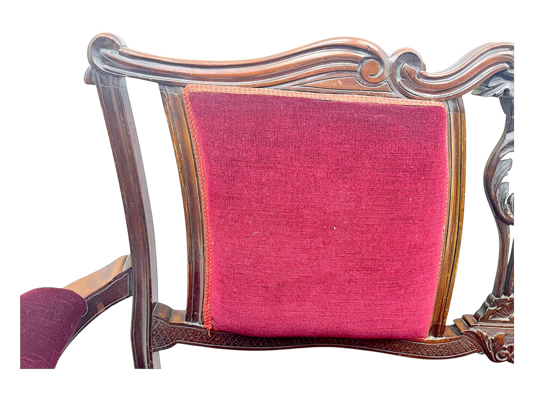 Late Victorian stained beech framed sofa, the backrests, seat and padded arms upholstered in deep red fabric, carved crest rail with scroll and foliate motifs supported by carved uprights, on cabriole supports with leaf carvings terminating in castors