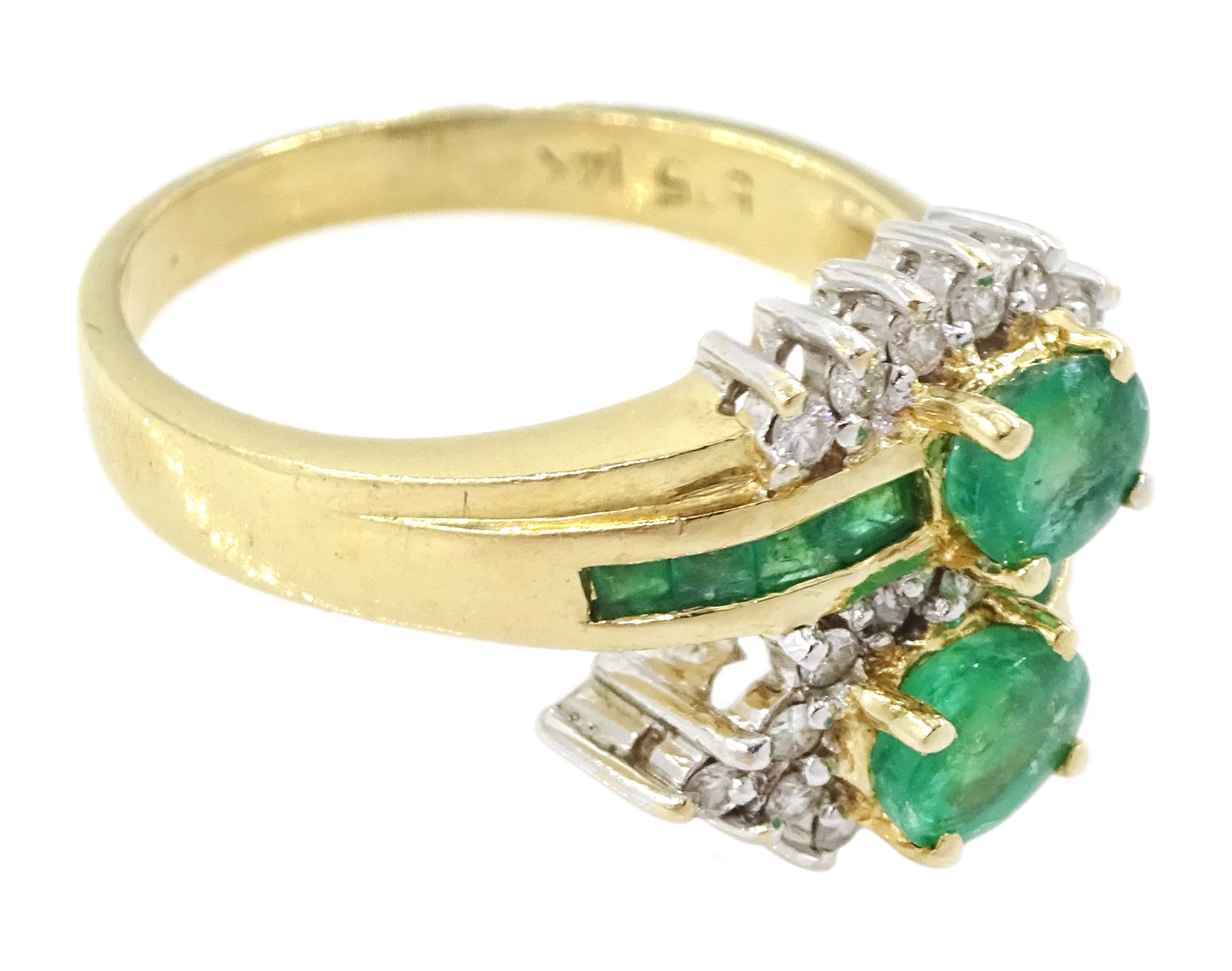 14ct gold emerald and diamond crossover ring, two oval cut emeralds with round brilliant cut diamond surround, with channel set calibre cut emerald shoulders, stamped 585