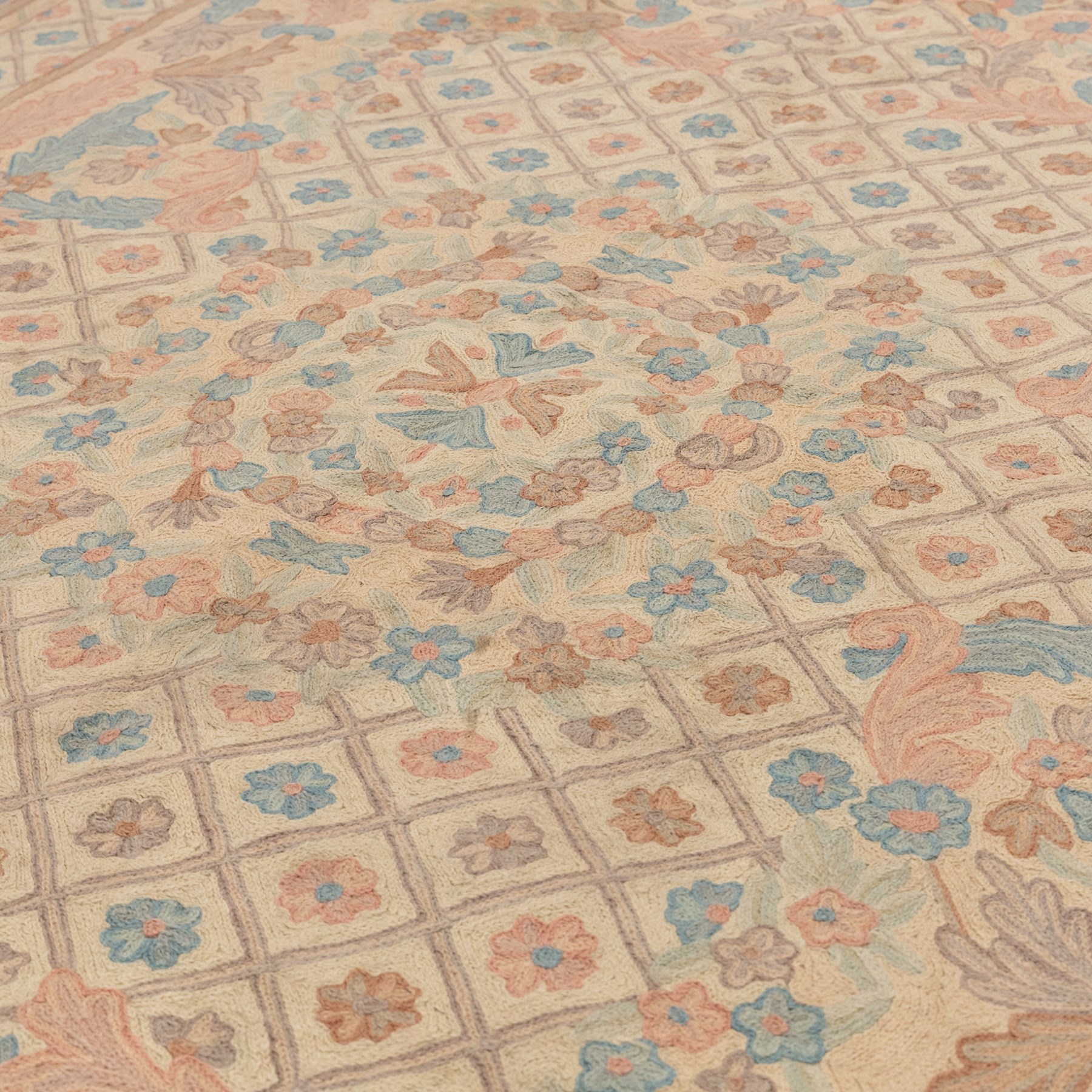 Aubusson design pale peach ground rug, woven with an all-over lattice design in rose and cyan with central floral bouquet medallion, the scrolling acanthi and flowerhead spandrels contained within a lattice guard band