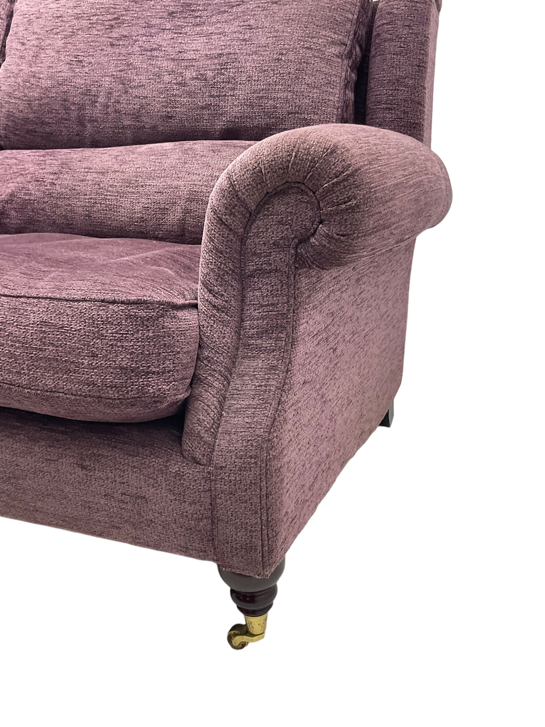 Parker Knoll - pair of large two-seat sofas upholstered in purple fabric, turned mahogany finish front feet with brass cups and castors 