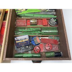 Meccano - large quantity of loose parts including various plates and strips, flanged plates, pulleys, axle rods and crank handles, wheels and tyres, gear wheels, brackets, nuts & bolts, various manuals; predominantly red and green; some in compartmentalised wooden trays
