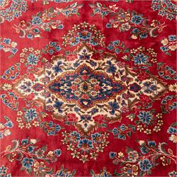 Fine Persian crimson ground Kashan carpet, the busy field with a central floral pole medallion surrounded by bouquets of flowerheads and trailing foliage, the shaped cyan spandrels similarly woven, enclosed by a wide foliate guard band of stylised palmettes and floral designs