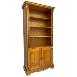Traditional pine open bookcase on cupboard, fitted with three adjustable shelves over a double cupboard with panelled doors