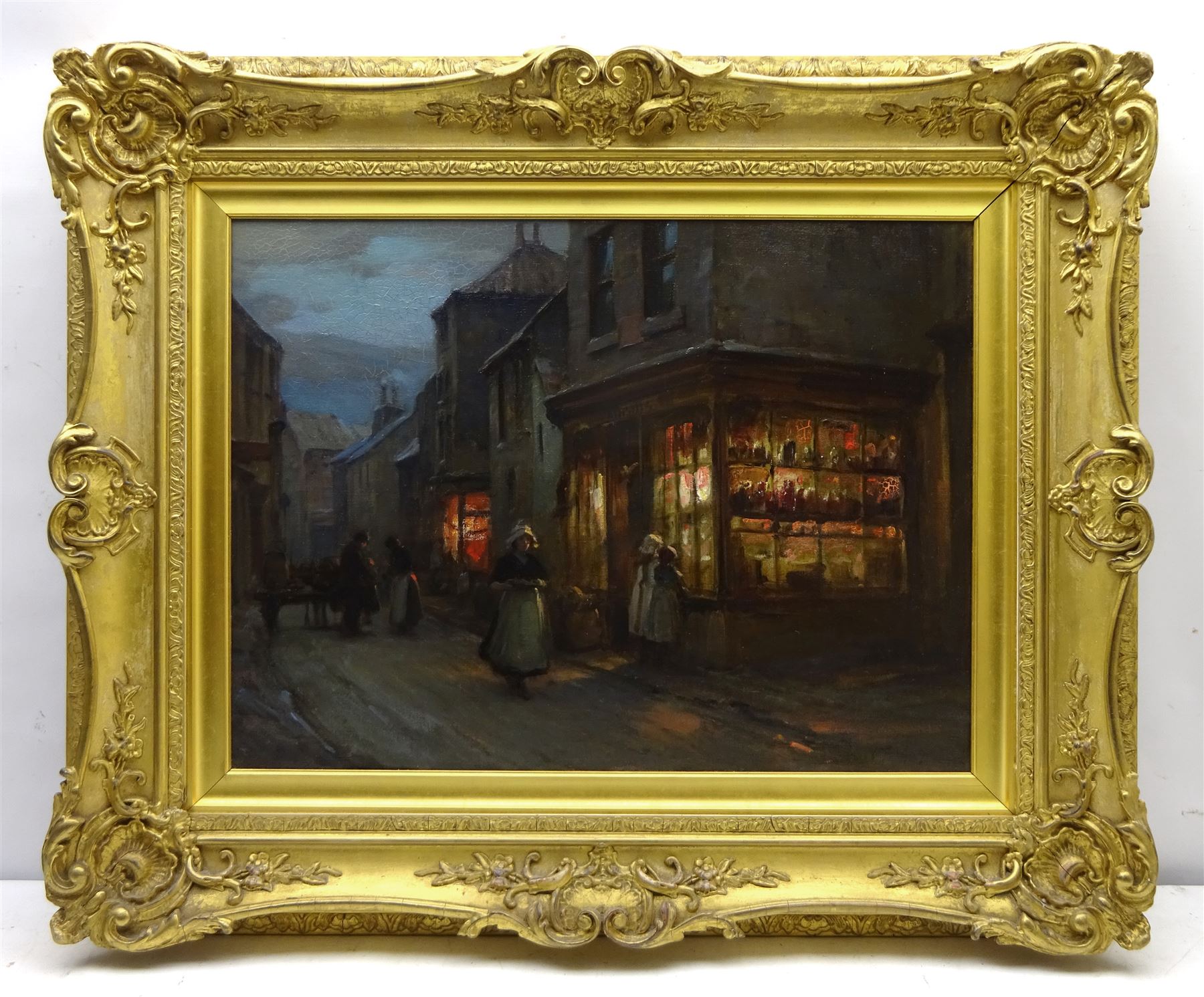 William Pratt (Scottish 1855-1936): 'Evening at Staithes' - the High Street, oil on canvas signed and dated 1909, titled on original label verso 45cm x 60cm 
Notes: Pratt seemingly visited Staithes multiple times in the early 1900s, as the companion to this picture, 'In the Shallows' (sold by Lyon & Turnbull 27/01/16, lot 536), in an identical frame and also depicting Staithes, is dated 1910. The shop in the foreground was a grocery run by Joseph Verrill, described in 1911 as 'grocer and agent for W & A Gilbey Ltd, Wine and Spirit Merchants'. He was often assisted by his two daughters, Lavinia and Hannah. The Verrills were one of the largest families in Staithes; Joseph Verrill Snr (1839-1910) was first coxswain of the Staithes lifeboat, and Isaac Verrill (1811-1895), a fisherman, was photographed by Frank Meadow Sutcliffe (1853-1941). The building became the gift shop of W & H Dean in the 1950s, and is now the Endeavour Café.