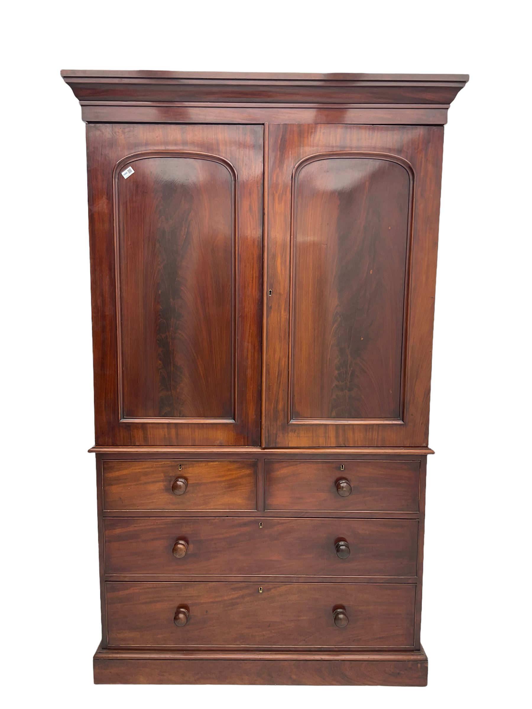Victorian mahogany linen press, projecting moulded cornice, two doors with arched panels enclosed four linen slides, the lower section fitted with two short and two long drawers, on plinth base