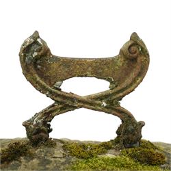 19th century cast iron boot scraper, with scrolled upright mounts, set into a rectangular moss-covered stone base