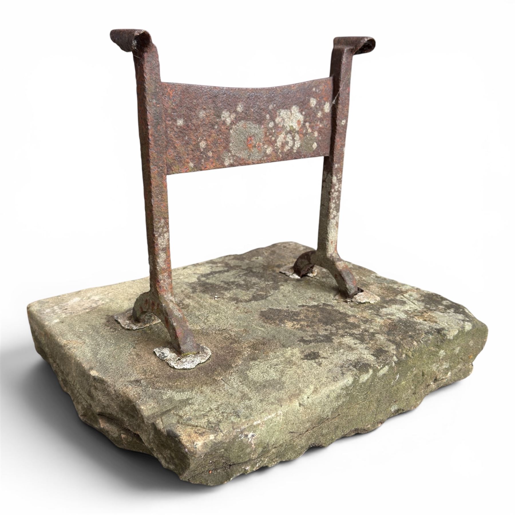 19th century cast iron boot scraper, mounted on a rectangular hewn stone slab base, with scrolled twin upright supports and scraper bar, in weathered finish