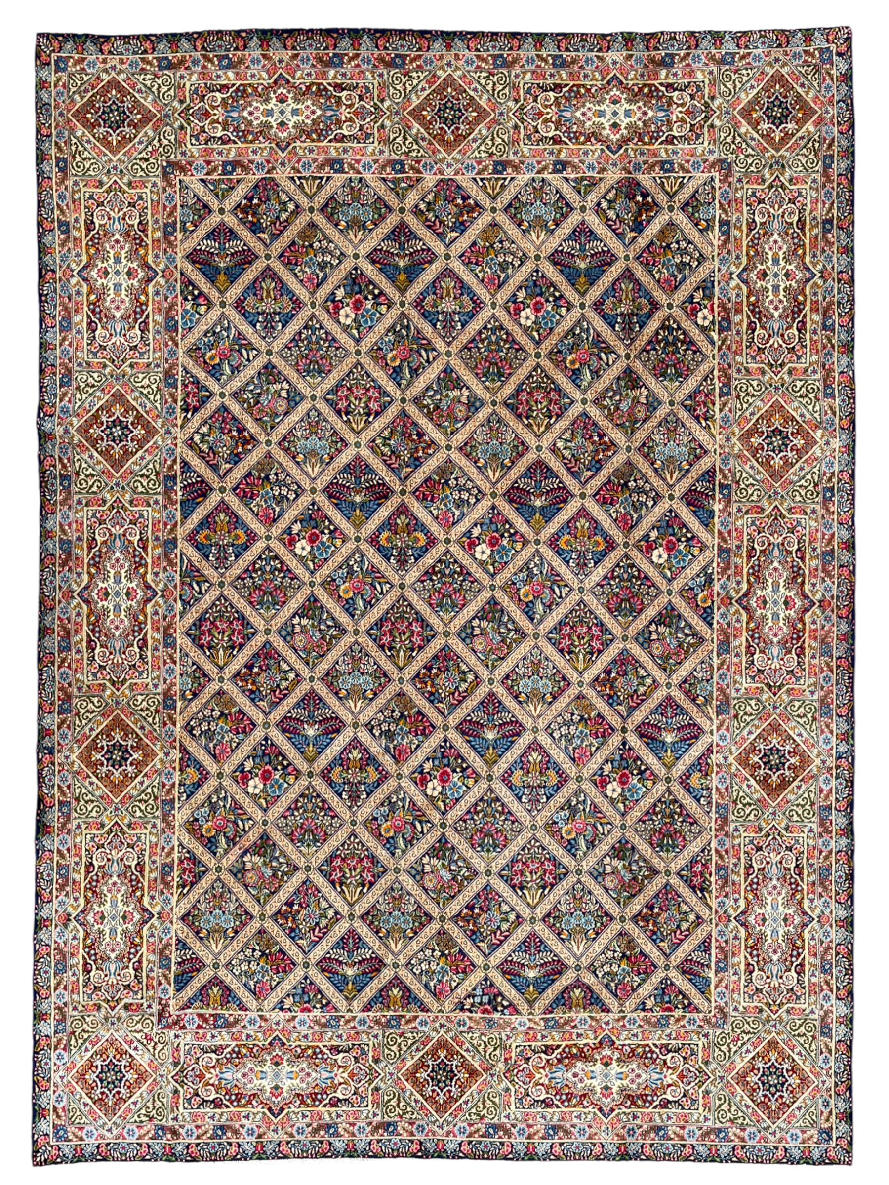 Persian Kirman indigo ground carpet, the field with repeating lozenge tiles with overall floral decoration, the main border with floral panels enclosed by the guards