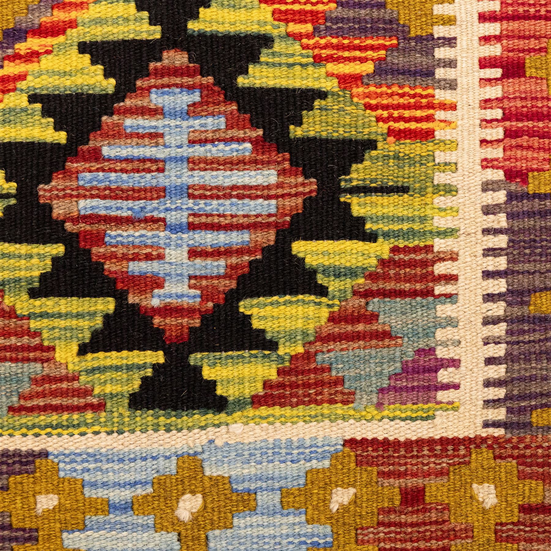Afghan Maimana flatweave kilim, central field features large bold nested diamond motifs and stylized geometric lozenge patterns on olive purple, blue, and green tone ground, border stripe in mustard ground, and fringe