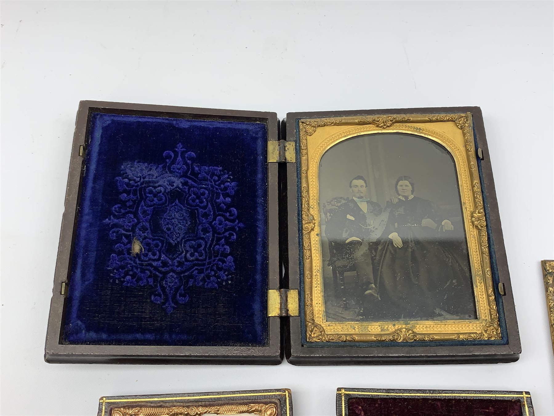 A Victorian ambrotype photograph in gilt surround and Vulcanite type Union case, decorated in low relief to front and verso with a female figure upon horseback, H12.5cm, together with a leather case daguerreotype, and a further loose example. (3).  