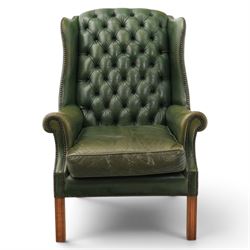 20th century green leather wingback button backed armchair, brass studded trim, with scrolled arms raised on oak supports