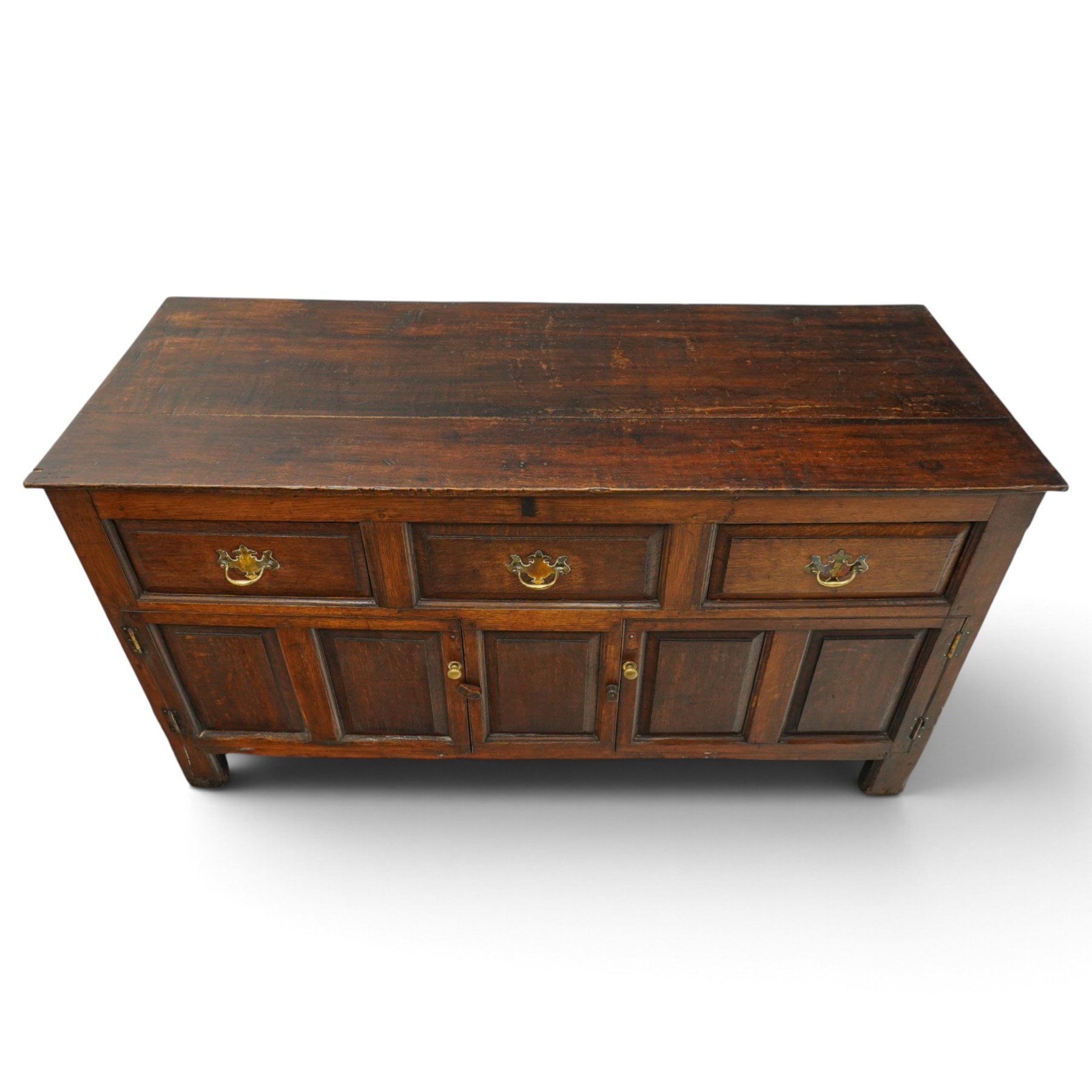 18th century oak dresser base, rectangular top over three drawers, fitted with twin panelled hutch-cupboard doors flanking central fielded panel, raised on stile supports
