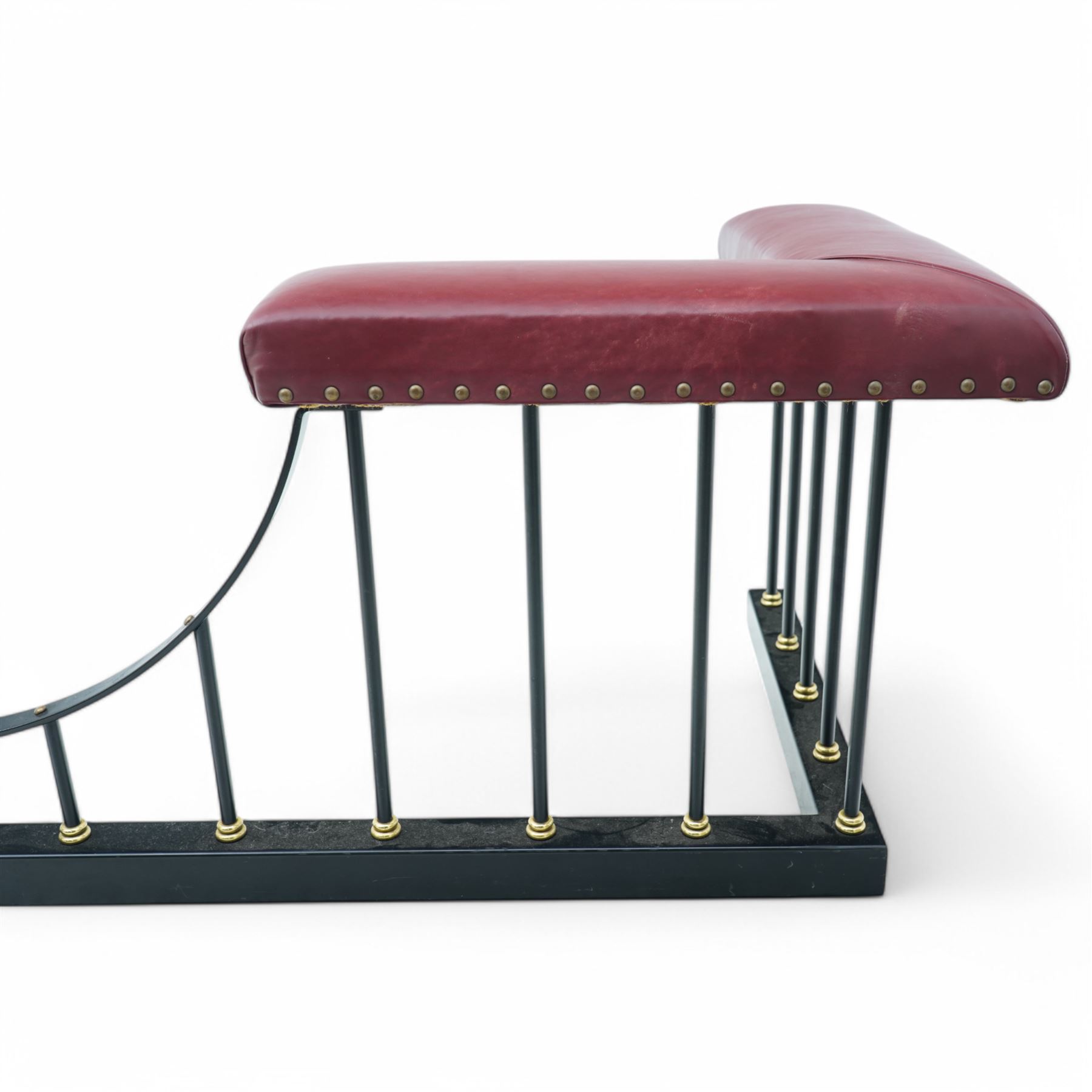 Wrought metal and brass fire fender, L-shaped corner seats upholstered in burgundy fabric with stud bands, dished centre on balustrade and plain curb  