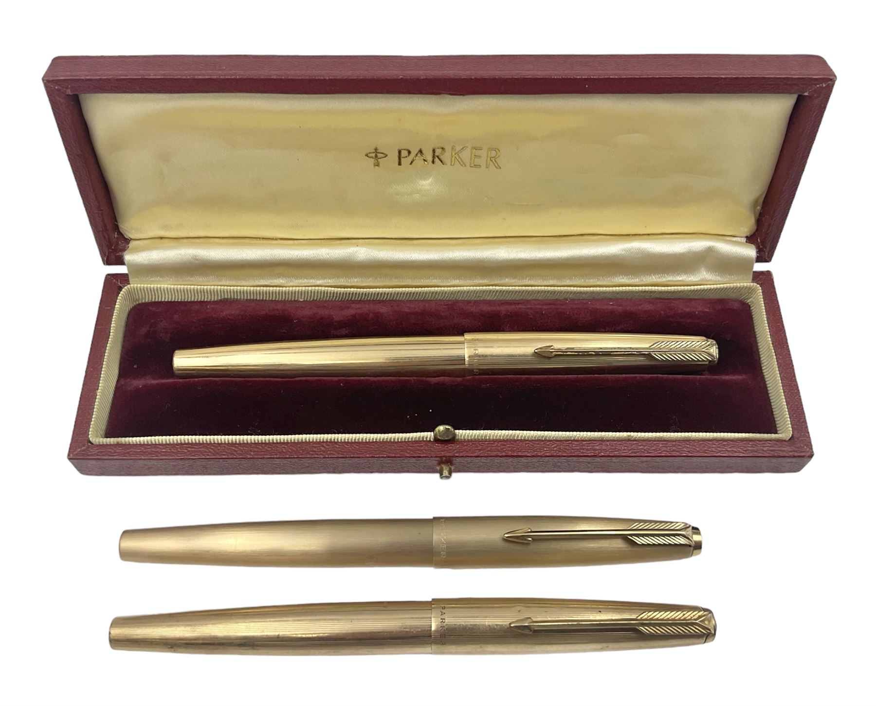 Three rolled gold Parker fountain pens, comprising an example with a gold nib marked 14K 585 and barrel with a shell stamp, a Parker 61 fountain pen with inset gold arrow to the nib, and another similar, all with striated decoration and arrow clips to the caps, L13cm, one with box