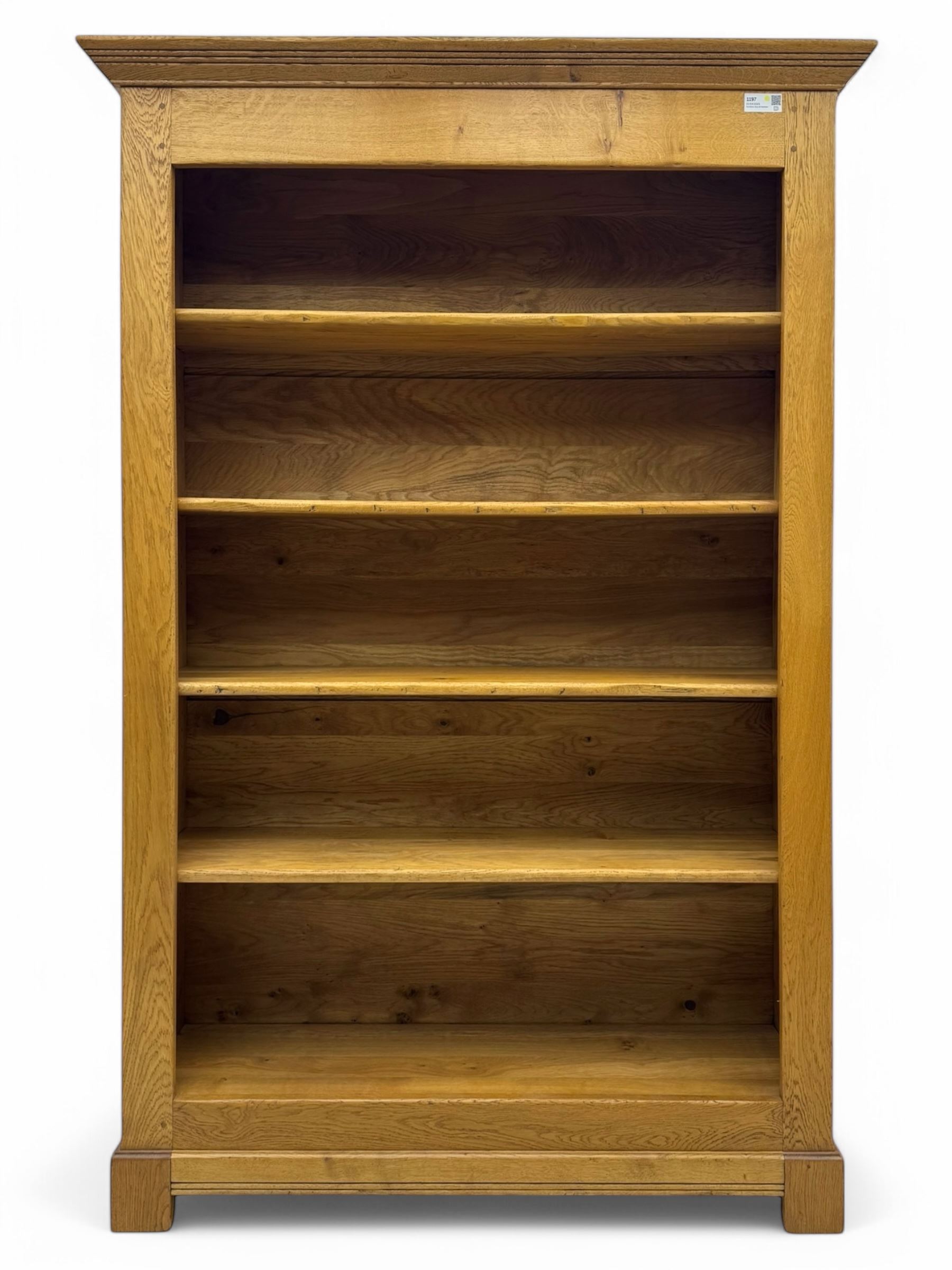 Contemporary French provincial design oak open bookcase, with projecting moulded cornice above a boarded back, fitted with four adjustable shelves, on bracketed plinth base