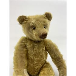 Early 20th century German teddy bear c1920, probably Steiff or Bing, with wood wool filled humped back golden mohair body, swivel jointed head with glass eyes and brown vertically stitched nose and mouth, jointed limbs with elongated arms and felt paw pads with black stitched claws H18