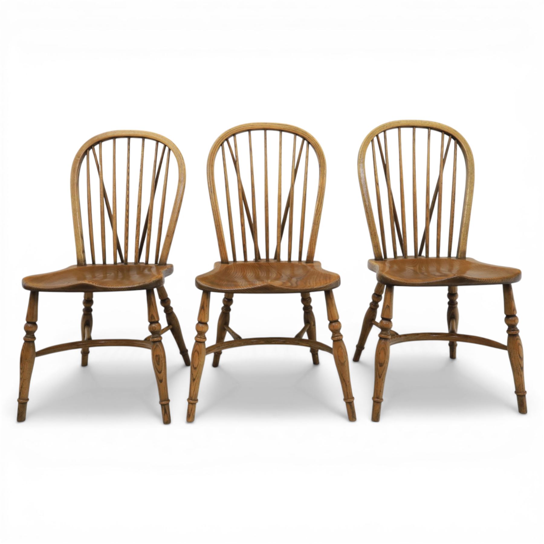 Traditional elm and beech Windsor dining chairs, each with hoop back and turned spindles over a shaped solid seat fitted with loose floral upholstered cushions, raised on turned tapering supports united by crinoline stretchers