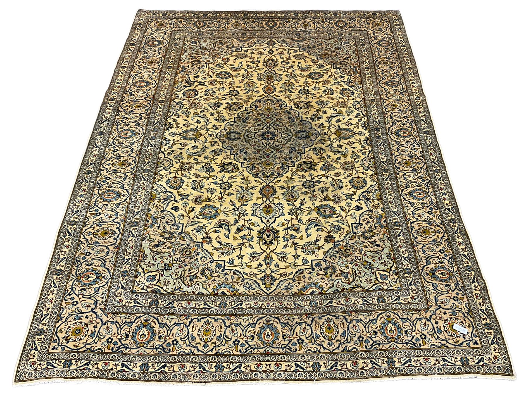 Persian Kashan golden ivory ground carpet, the central medallion surrounded by a field of interlacing branch and stylised plant motifs, the guarded border with scrolling design decorated with flower heads 
