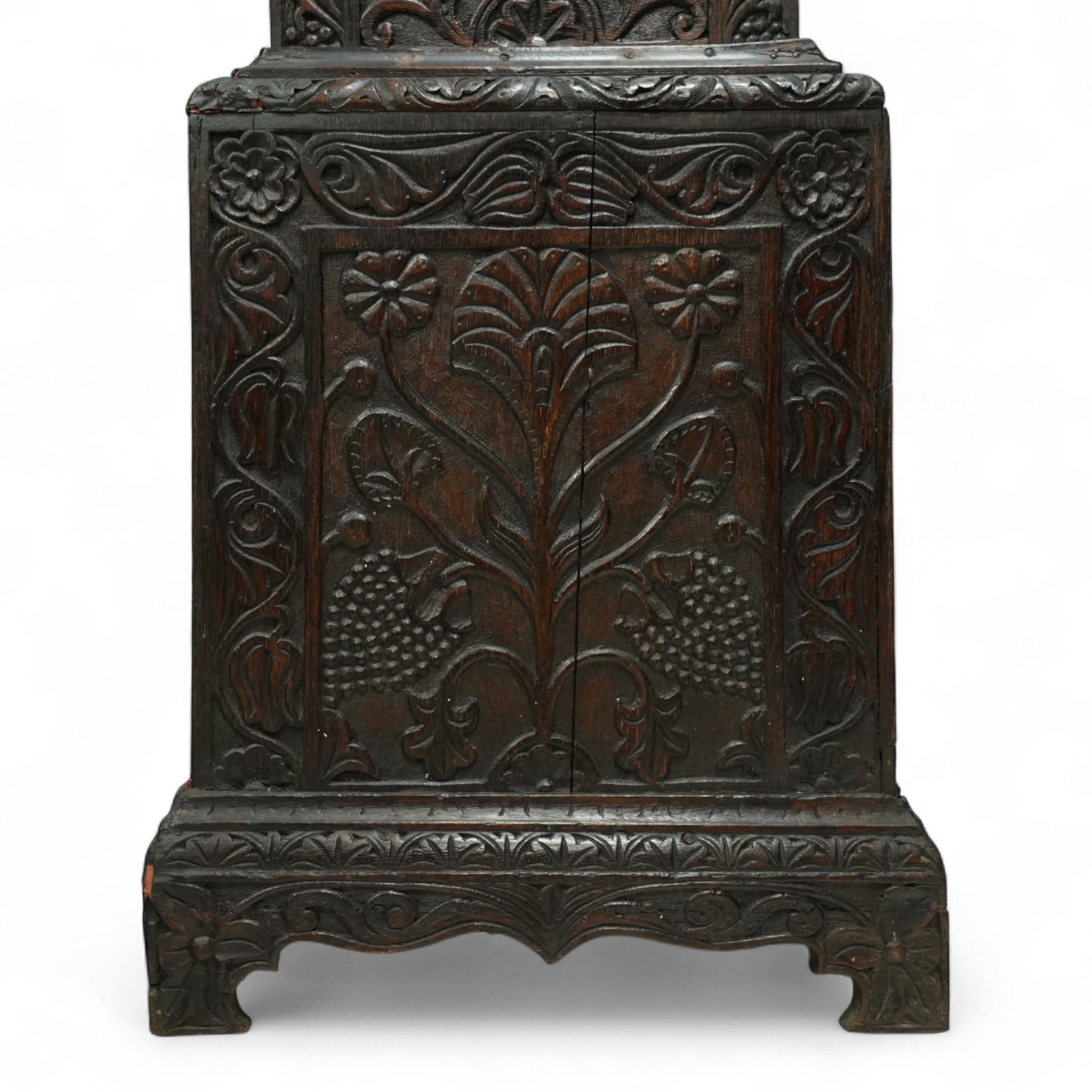 Man Beckett (I) of Stockton on Tees (Co Durham) - 8-day early 18th  century longcase clock in a  profusely carved oak case, with a caddy top, turned finials and attached barley twist pilasters to the break arch hood door, long trunk with carving and a conforming long rectangular door carved with a Celtic depiction of the tree of life, corresponding plinth with a carved and decorative base, break arch brass dial with a rounded brass surround, cast spandrels and silvered boss with the makers name to the arch, matted dial centre with seconds dial, ringed winding apertures, square date aperture and fettled steel hands, silvered chapter with Roman numerals, five minute Arabic's, half hour markers, minute and inner quarter hour tracks, dial pinned to a five pillar movement with inside countwheel striking and a recoil anchor escapement, striking the hours on a bell. With weights and pendulum.
Man Beckett (I), (first name is a biblical name short for Manasseh), was the first member of the Beckett family of prodigious clockmakers working in the North-East of England from 1720 until 1884.