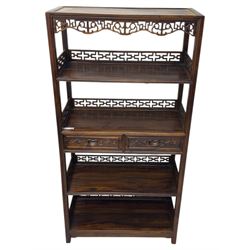 Early 20th century Chinese hardwood display étagère bookcase, the rectangular open tiered frame with pierced frieze and geometric openwork gallery to each shelf, fitted with two short drawers carved with stylised lotus motifs, supported on square uprights with pierced apron and integral gallery rails