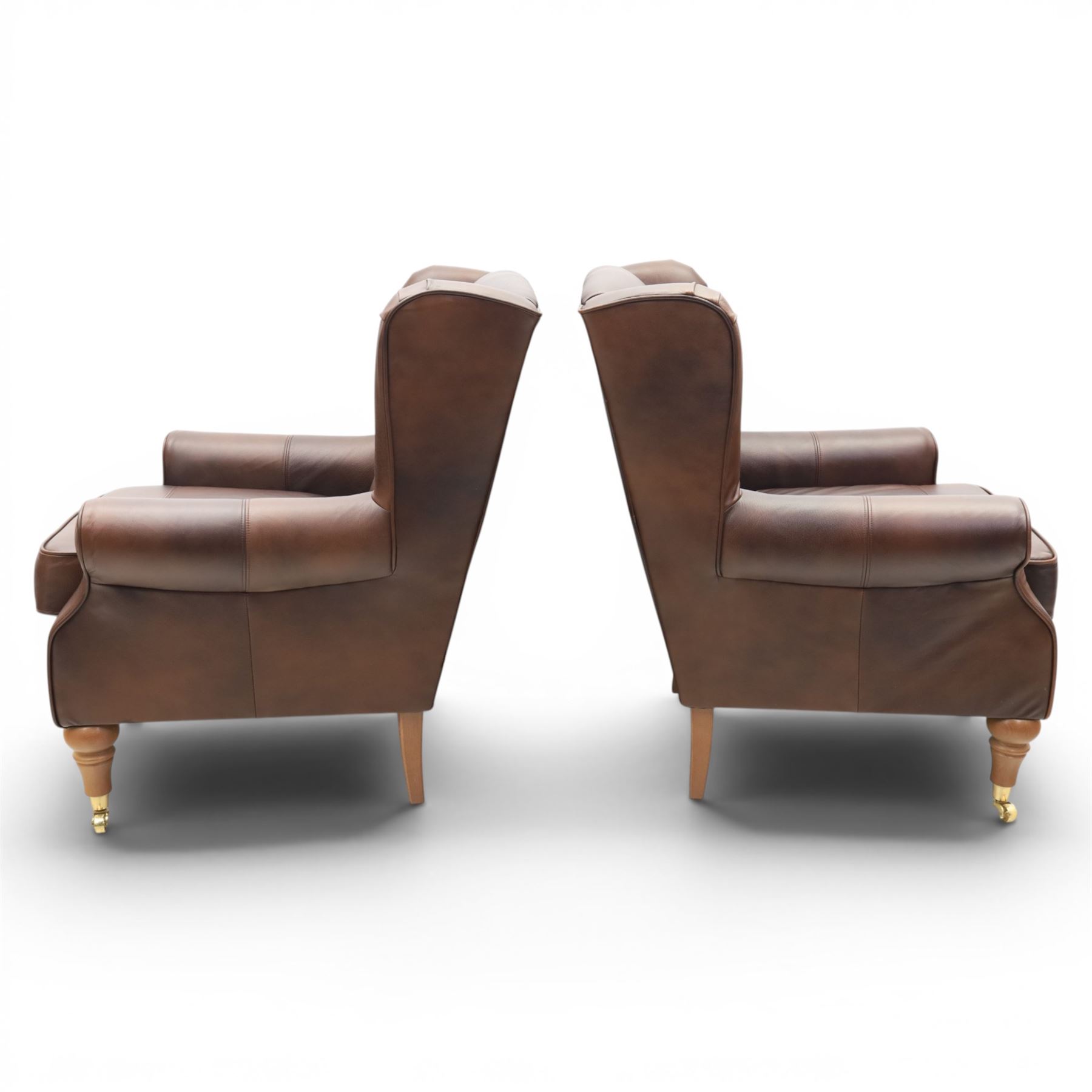 Marks & Spencer - Pair of brown leather wing back chairs, raised on light stained supports with castors