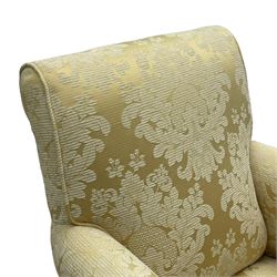 Traditionally shaped hardwood-framed armchair, rolled back and arms, upholstered in pale gold and cream damask fabric with repeating foliate pattern, on turned feet with brass cups and castors