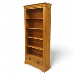 Contemporary oak bookcase, with moulded cornice above open shelved interior, fitted with four adjustable shelves and two short drawers with inset brass handles, panelled sides, plinth base