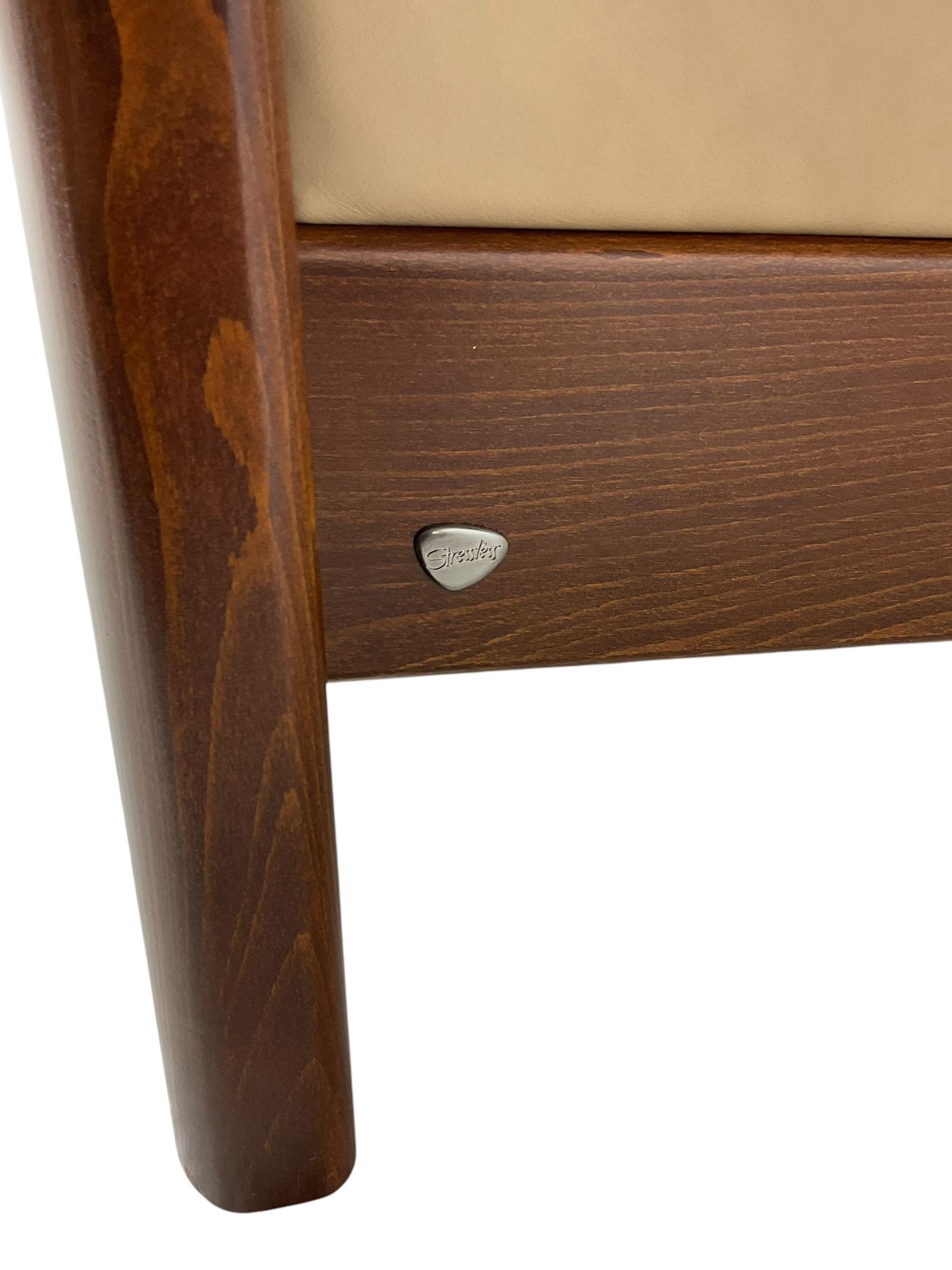 Ekornes Stressless - two-seat beech framed sofa, upholstered in beige-brown leather with stitched panel detailing, featuring curved armrests and high back supports with manual recline mechanism, raised on a dark-stained beech frame with sculpted supports