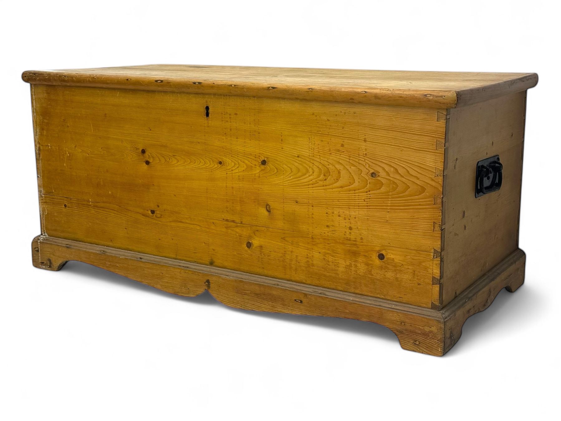 Late 19th century stripped pine blanket box, rectangular hinged lid enclosing main compartment with fitted candle box, wrought iron strap hinges and lock, black-painted side handles, on a shaped plinth base