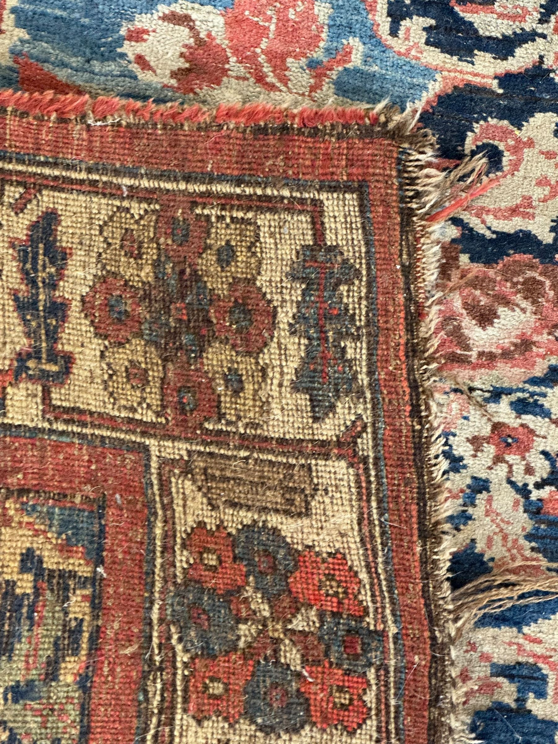 Persian Bidjar indigo ground rug, the busy field decorated with large floral motifs, the guarded ivory border adorned with repeating flower heads and stylised leaves