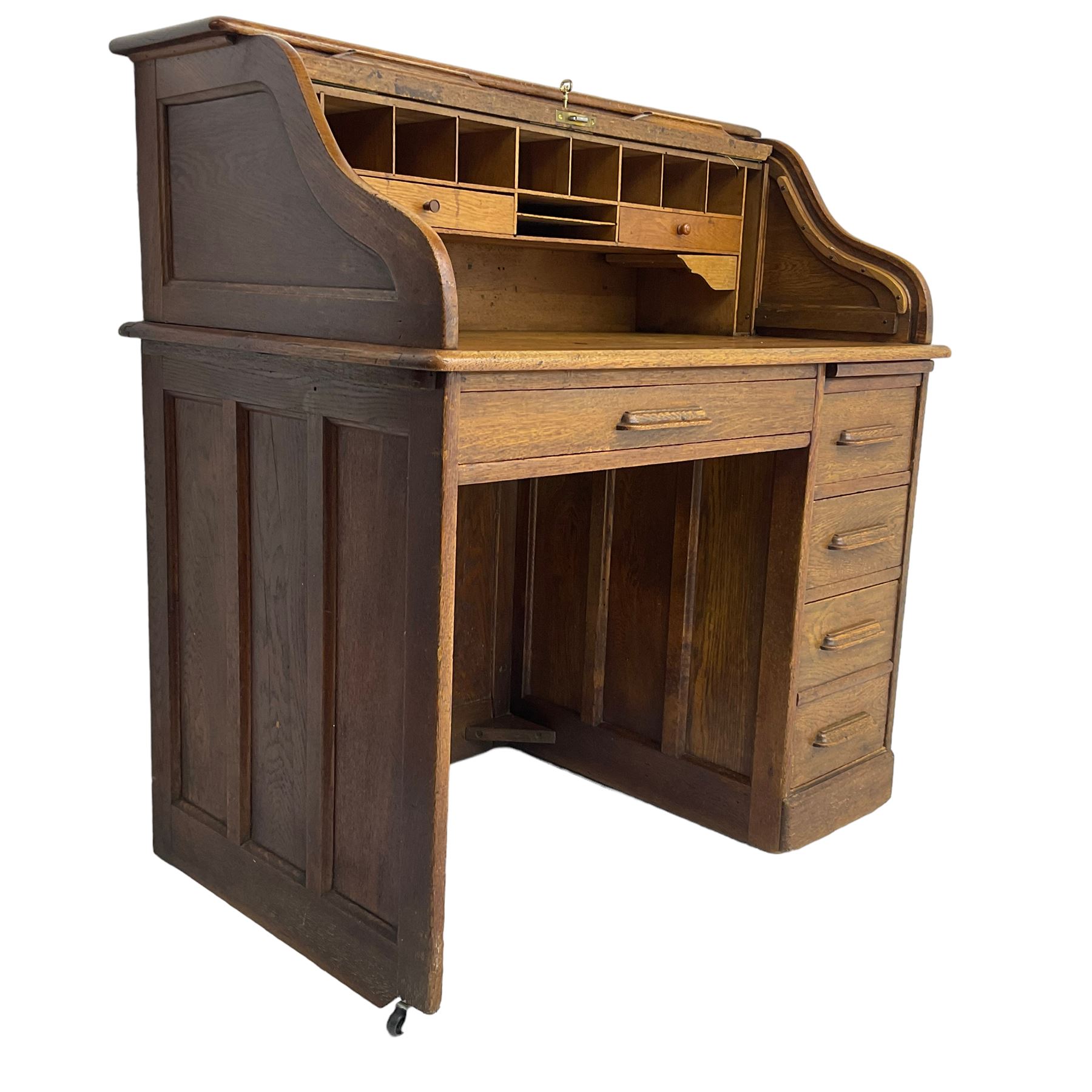 Early 20th century oak roll-top desk, the tambour enclosing pigeon holes and small drawers, the base fitted with slide, a single long drawer and three smaller drawers