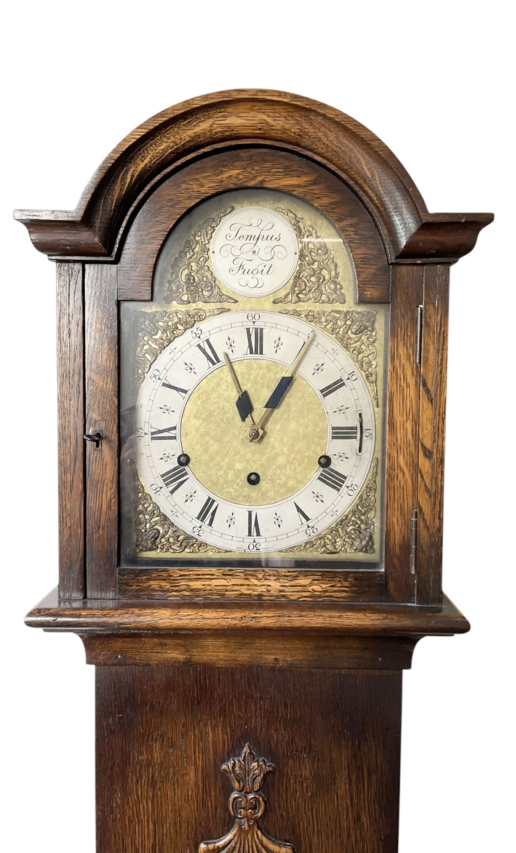 English-1930’s 8-day oak cased grandmother clock, with a break arch hood and trunk with applied carving, brass dial with silvered chapter ring and matted dial centre, three train Westminster chiming movement chiming the quarters and hours on12 gong rods. With pendulum.
