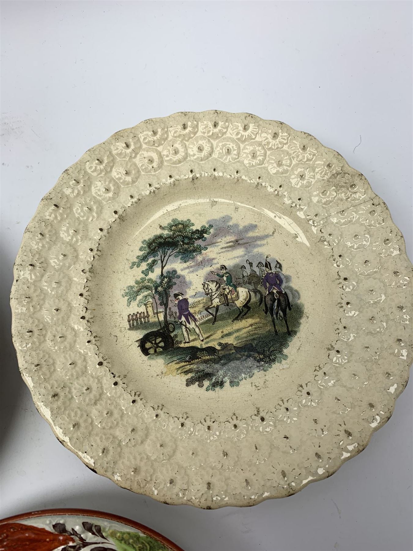 Three 18th/19th century nursery plates, comprising example decorated with central printed chinoiserie scene of pagoda, fence and two figures with bird, within a moulded swag and patera border, D18cm, a William Smith & Co example decorated in the Napoleon pattern with moulded floral border, with printed mark detailed Napoleon WS&Co and faint impressed mark WS&Co's Wedgewood beneath, D18cm, and a pearlware example decorated with chinoiserie figural scene within a moulded border, with overpainted decoration, collectors label beneath inscribed 'Early Wedgwood or Leeds 1750-60', D16cm

