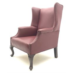  20th century wing back armchair, upholstered in studded red leather, raised on cabriole supports          