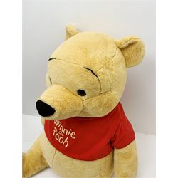 Very large plush covered figure of Winnie The Pooh in a seated position with black plastic eyes, black felt nose and eyebrows, red open mouth and T-shirt with name to front H42