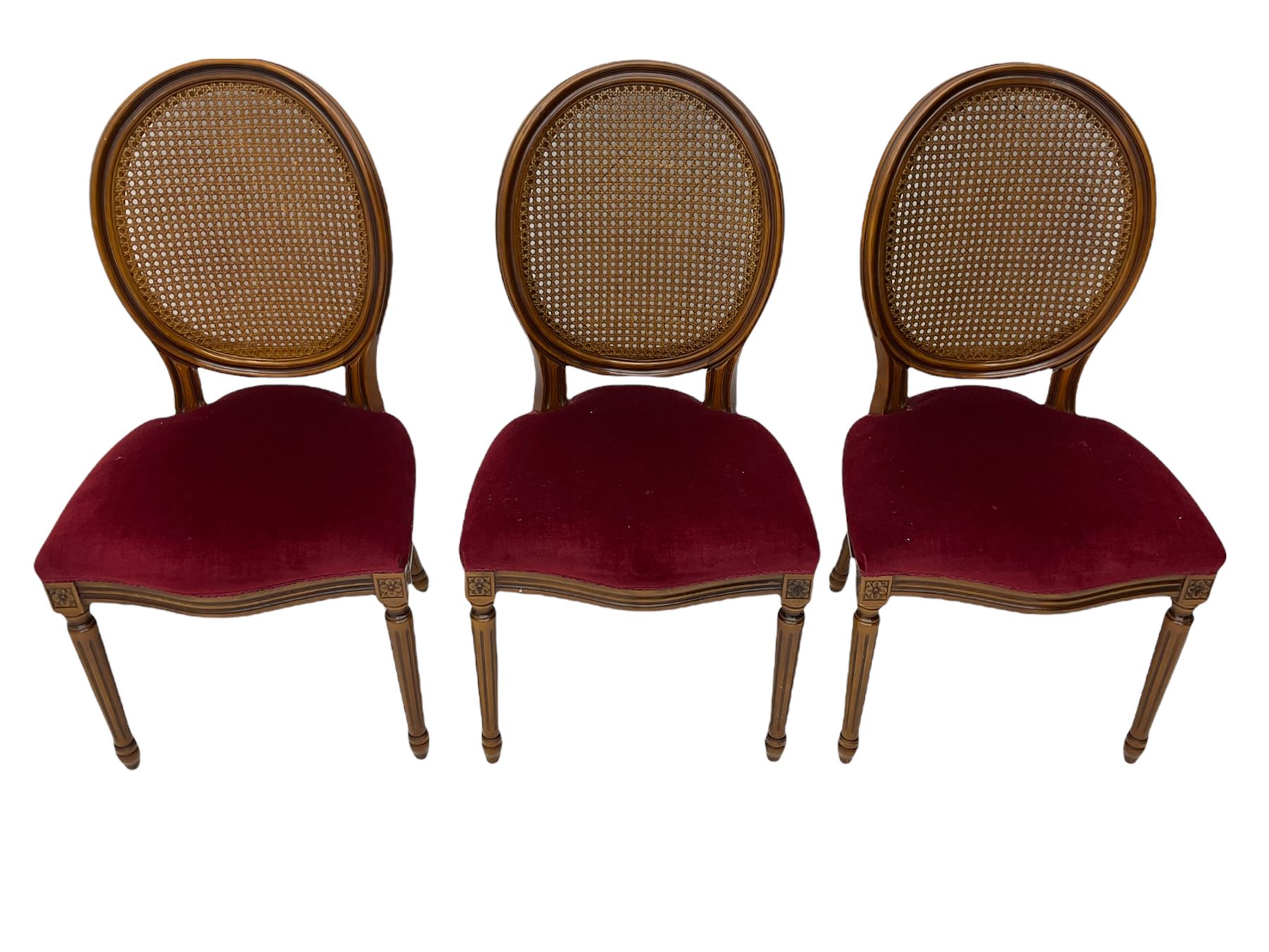Set six French style walnut finish dining chairs, oval cane bergere backs over serpentine seats upholstered in red, flower head carved fluted supports